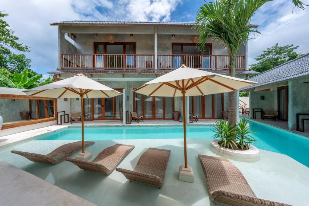 a villa with a swimming pool with chairs and umbrellas at Kano Uluwatu in Uluwatu