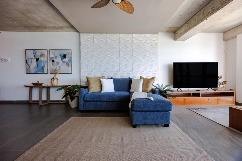 Una sala de estar con un sofá azul y un televisor en Atlantis 18 Breathtaking View Apt in San Juan, en San Juan