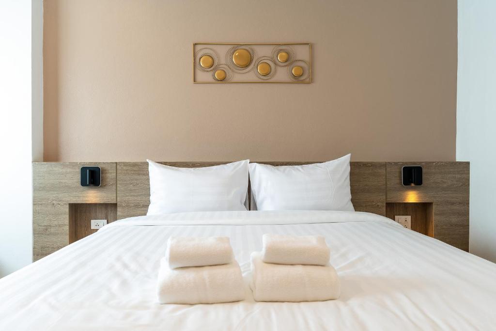 a bedroom with a white bed with two towels on it at Finn Hotel in Ban Fang Daeng