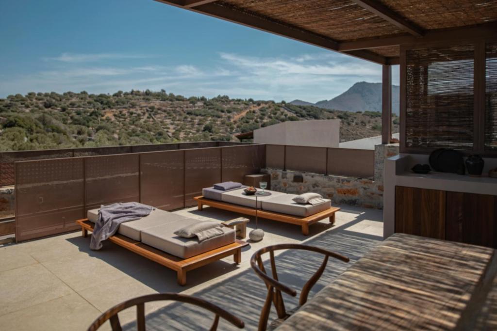 a patio with two beds and a table and chairs at Drakoni Luxury Suite, an Architectural Hideaway, By ThinkVilla in Agios Nikolaos