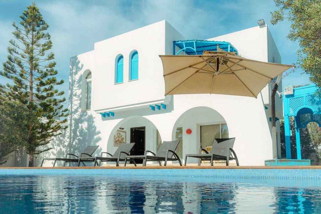 Villa Le Grand Bleu في ميدون: فيلا بمسبح مع كراسي ومظلة