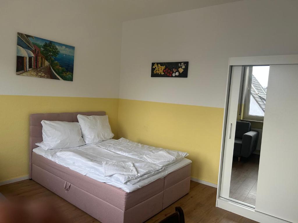 a small bed in a room with yellow walls at Hotel RI in Esslingen