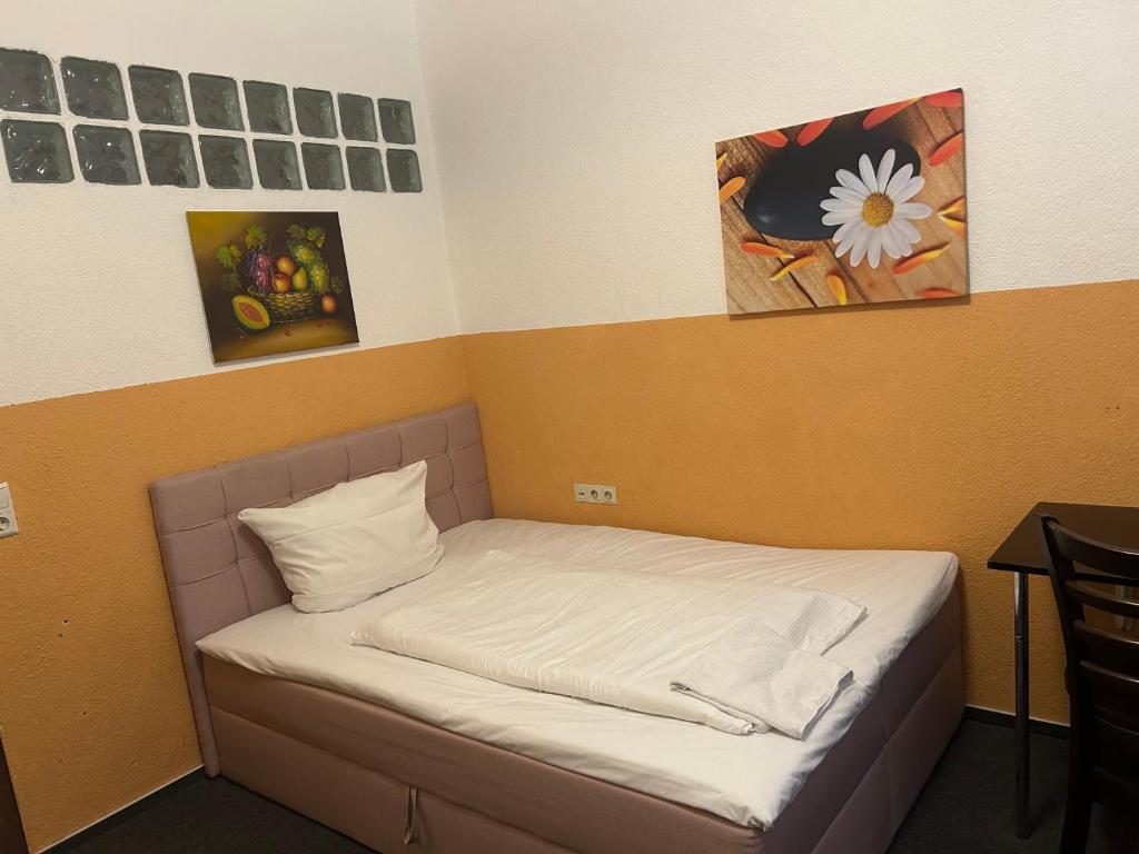un piccolo letto in una stanza con dipinti alle pareti di Hotel RI a Esslingen