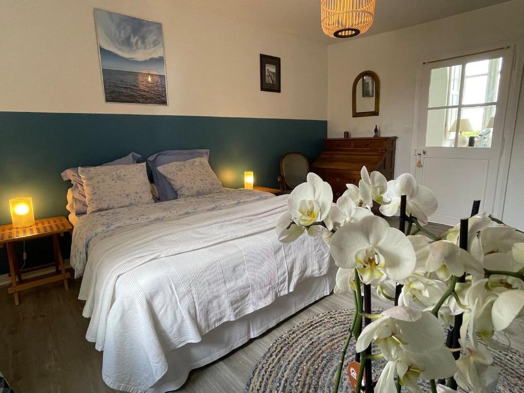 a bedroom with a bed with white sheets and flowers at Domaine de Bel Ebat in Paucourt