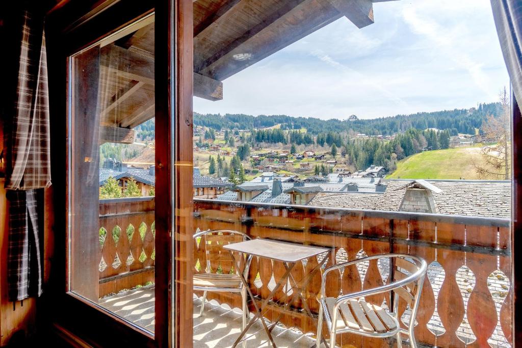 a balcony with a table and chairs looking out a window at Six-Deniers in Les Gets