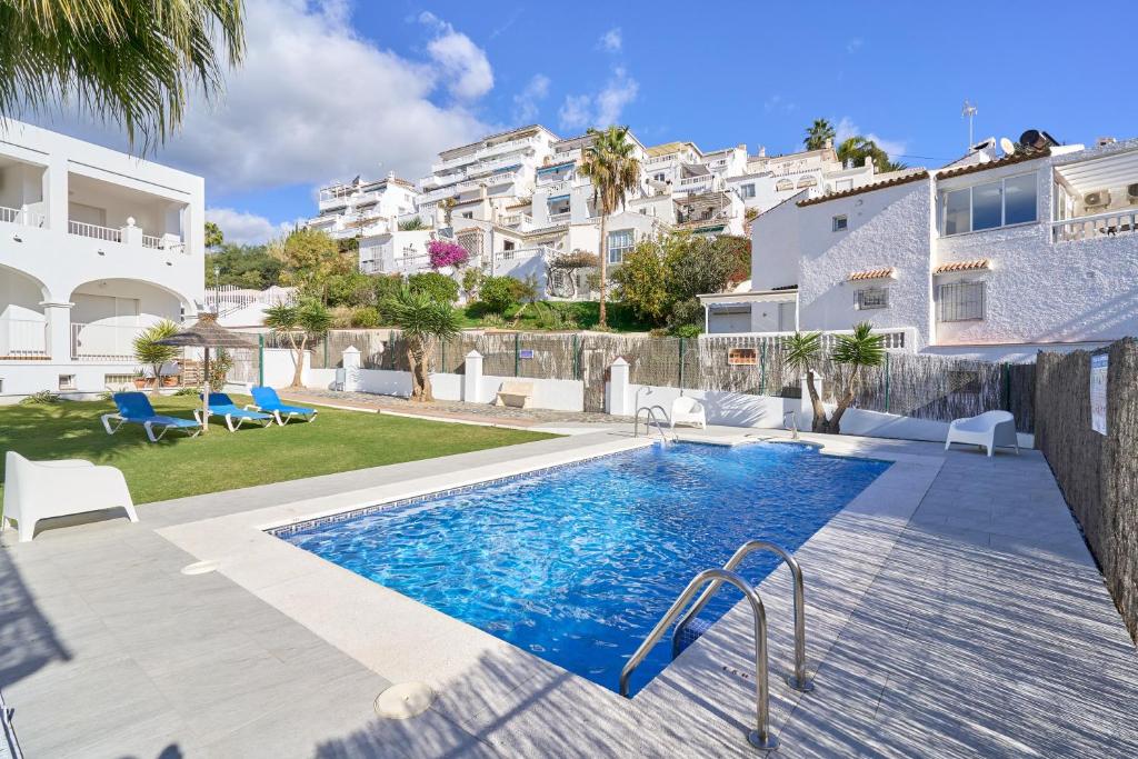 a villa with a swimming pool in front of a building at Apto 5 Almoraide Suites in Nerja