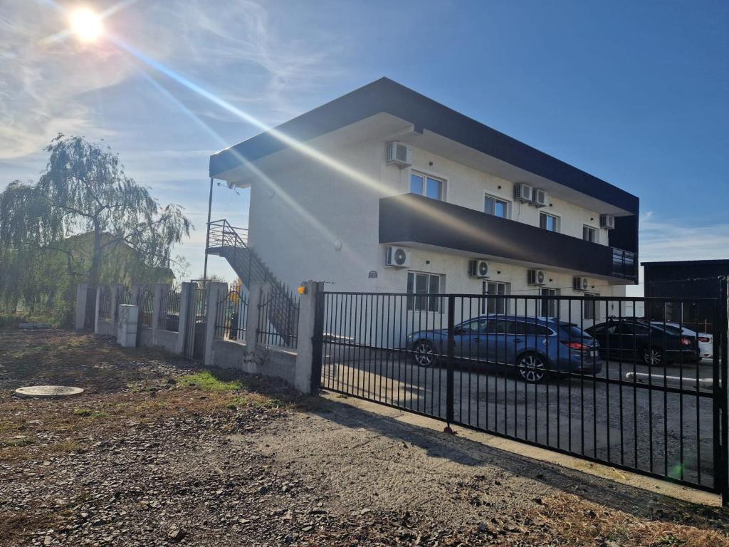 een gebouw met een auto geparkeerd naast een hek bij Apartament DOM in Moşniţa Nouă