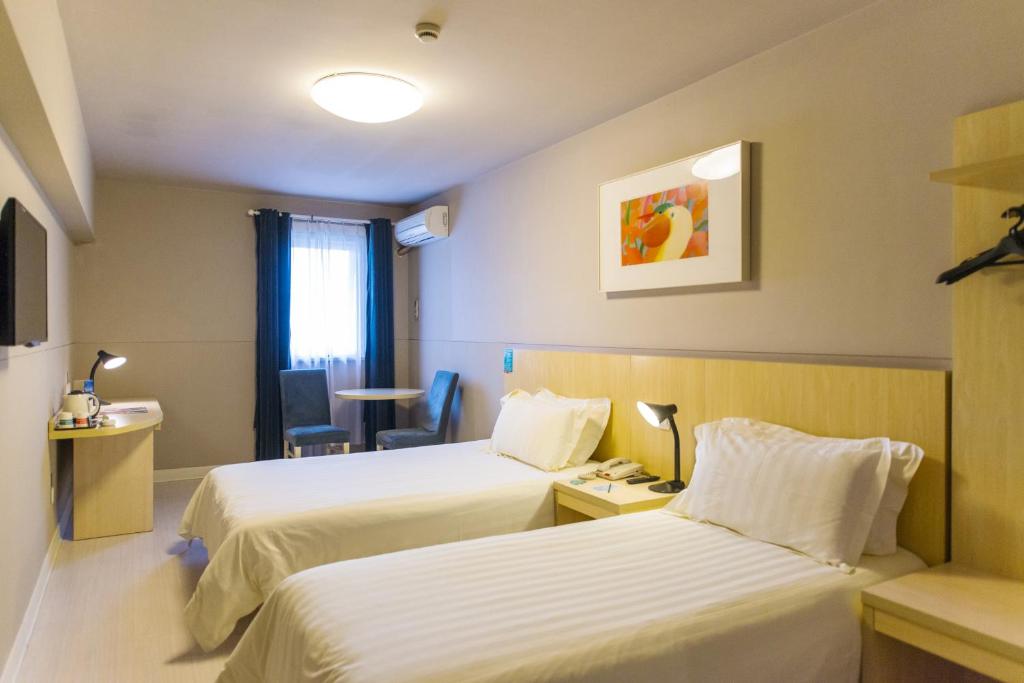 a hotel room with two beds and a table at Jinjiang Inn Wuhan Lingjiao Hu Wada Hotel in Wuhan