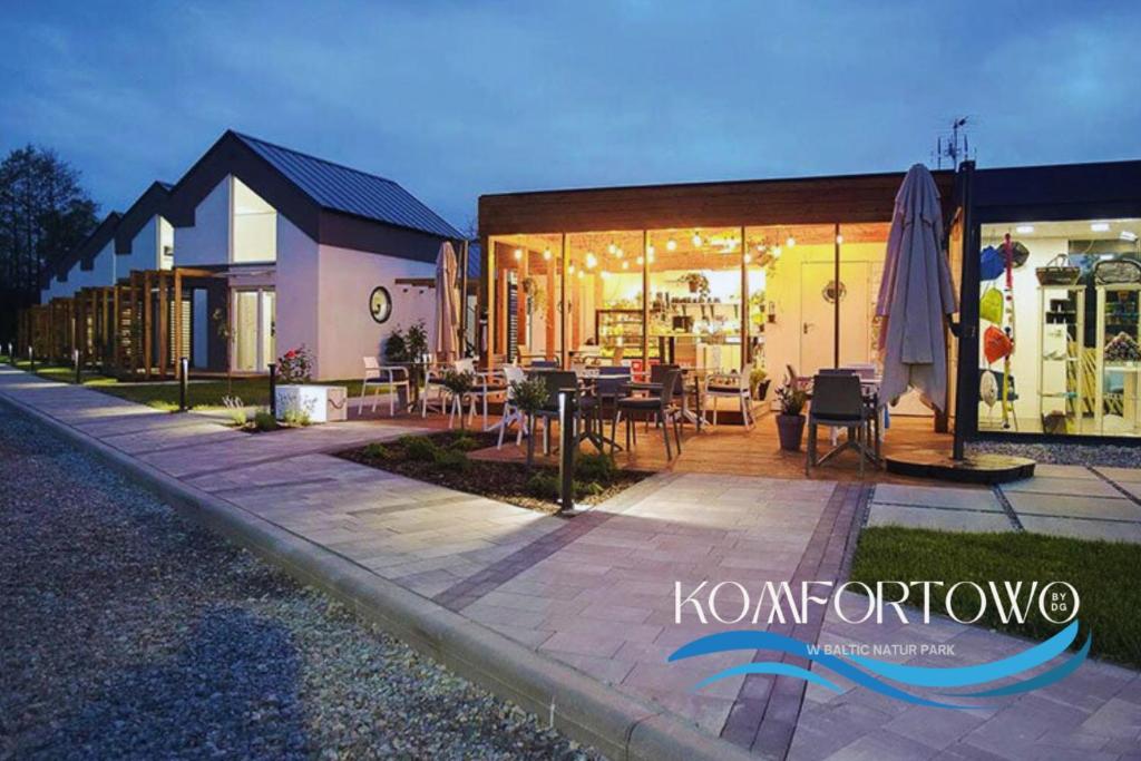 a building with a patio with tables and chairs at Domek w Baltic Natur Park Komfortowy 2 sypialnie klima alpaki mnóstwo atrakcji by DG in Niechorze