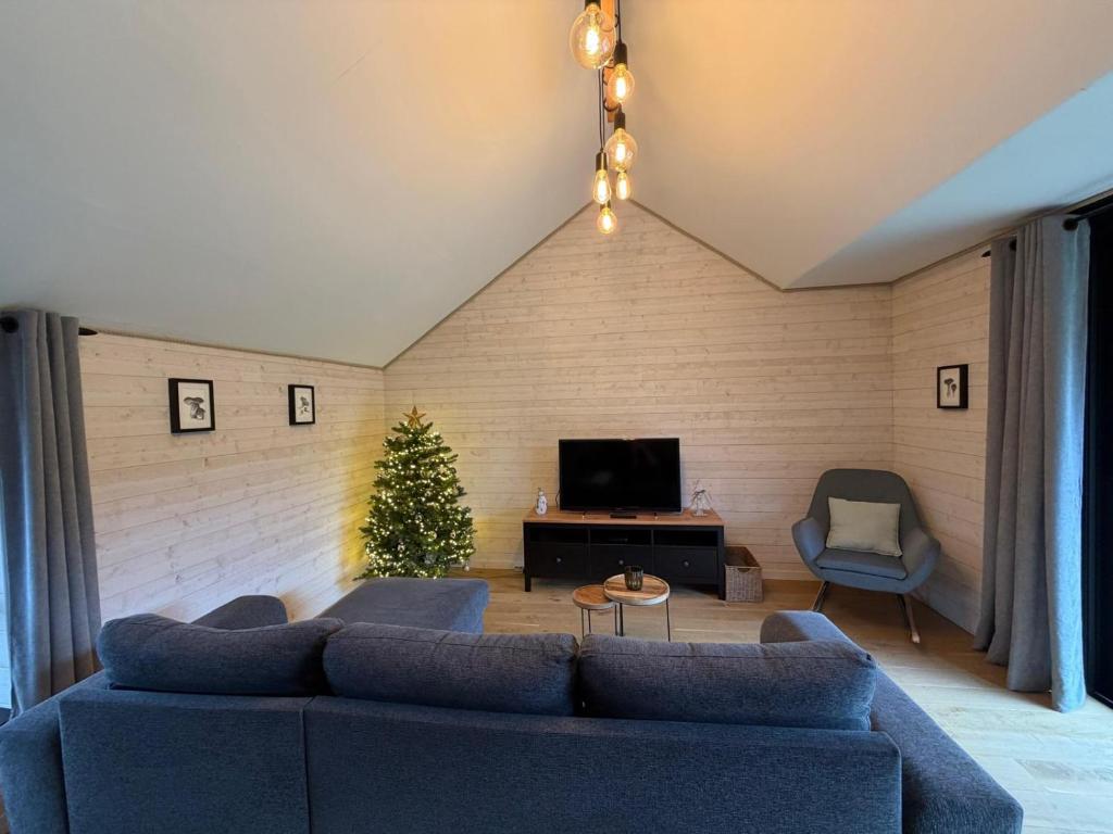 un soggiorno con un divano blu e un albero di Natale di Ambiance boisée Moustier a Stoumont