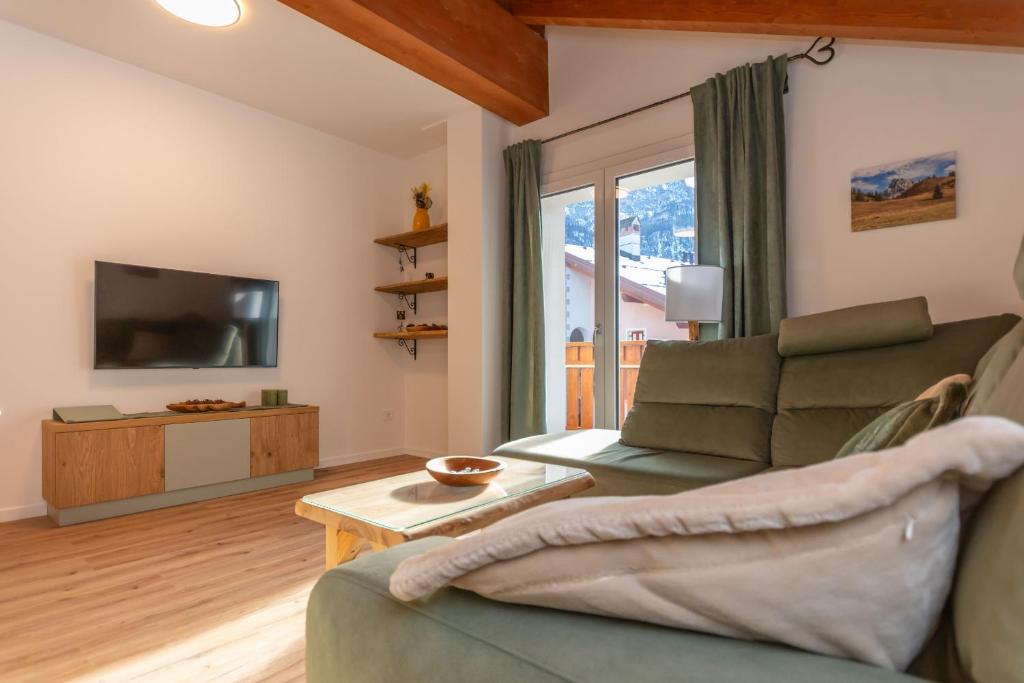 een woonkamer met een bank en een tv bij Hapina Dolomiti in Cencenighe