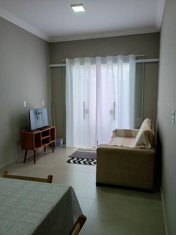 ein Schlafzimmer mit einem Sofa, einem TV und einem Fenster in der Unterkunft Casa bananeira in Bombinhas