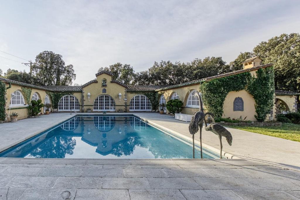 Una finca con piscina con dos pájaros parados al lado. en Masia Mimosa Montaña, en Darnius