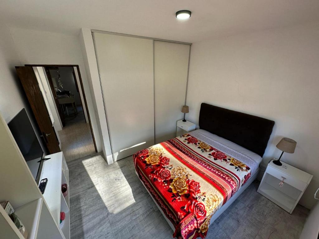 Un dormitorio con una cama con una manta colorida. en Casa con Patio y Parrilla Zona Golf, en Villa Gesell