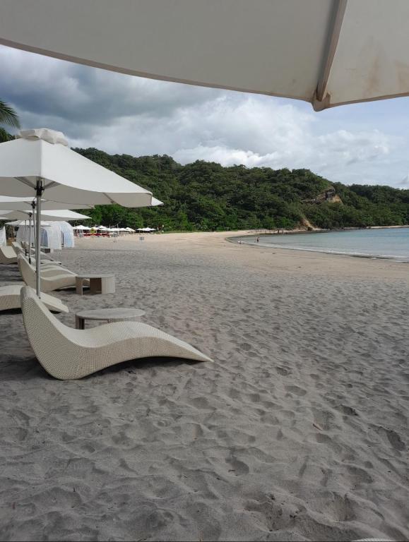 a beach with chairs and an umbrella on the sand at Pico de loro in Nasugbu