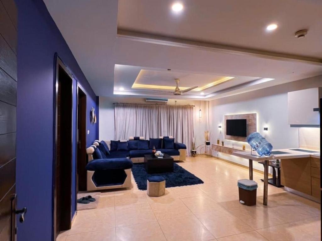ein Wohnzimmer mit einer blauen Couch und einem Fernseher in der Unterkunft Osma Living Apartment Lahore in Lahore