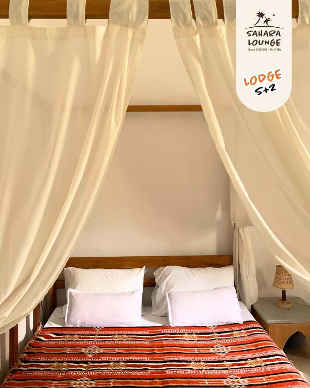 a bedroom with a canopy bed with white curtains at Sahara Lounge in Tozeur