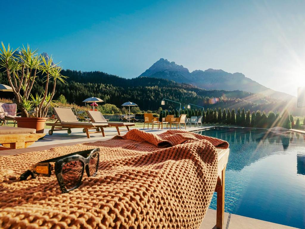 Eine Brille liegt auf einem Bett neben einem Pool. in der Unterkunft Helmhotel in Innichen