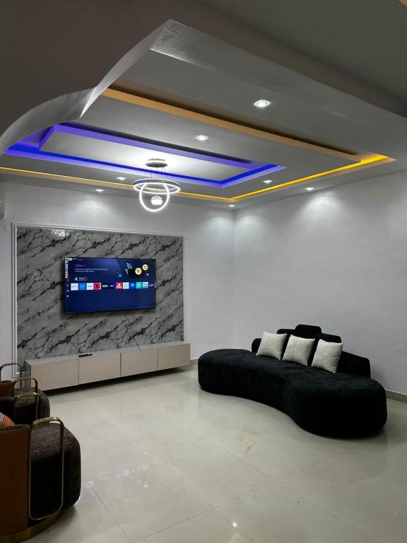 a living room with a black couch and a tv at Modern 3-Bedroom Luxury Home in Lekki Phase 1 in Lekki
