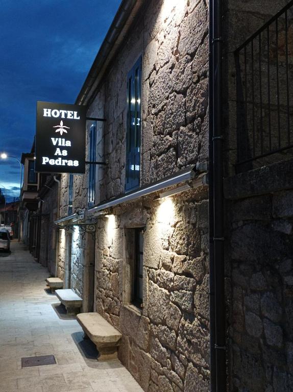 a building with a sign on the side of it at Hotel Vila As Pedras in Roxos