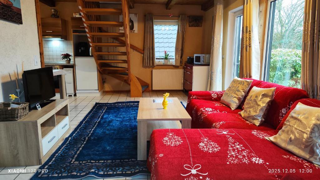 un soggiorno con un divano rosso e un tavolo di Ruhiges Elbhäuschen nahe Hamburg a Hollern-Twielenfleth