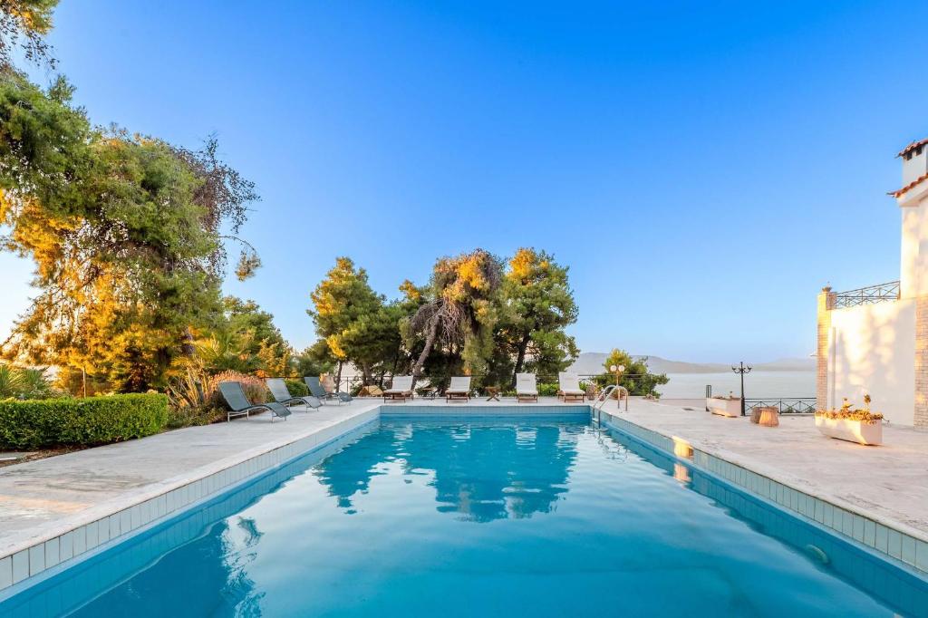 a swimming pool with blue water and trees at Seaview Villa Cleopatra - Private Pool & Tennis Court in Kalamos