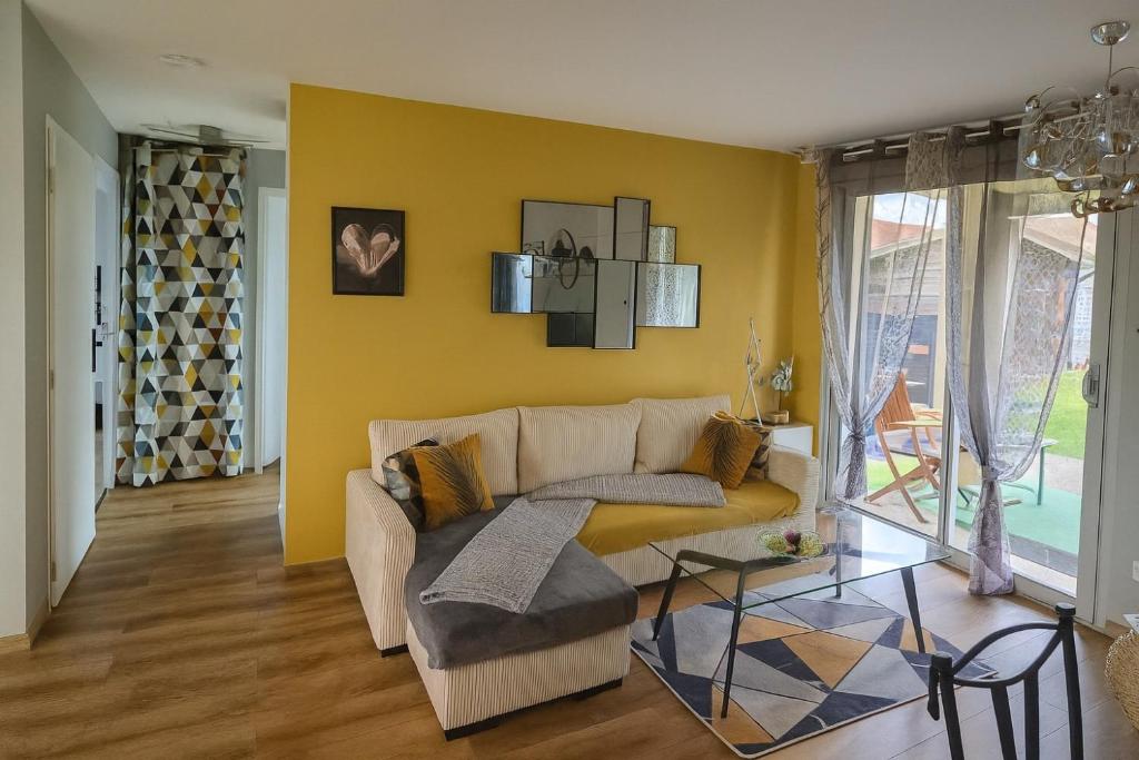- un salon avec un canapé et un mur jaune dans l'établissement Maison Chardonnerets - Poitiers, à Biard