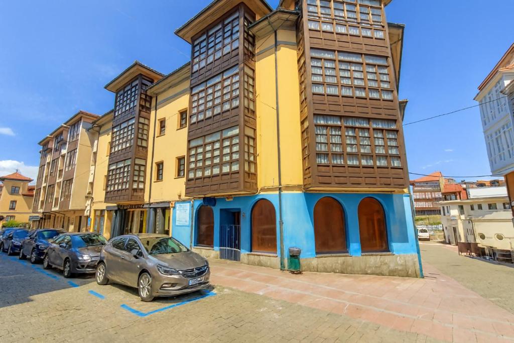 een geel gebouw met auto's ervoor geparkeerd bij Apartamento Vacacional La Rula in Llanes