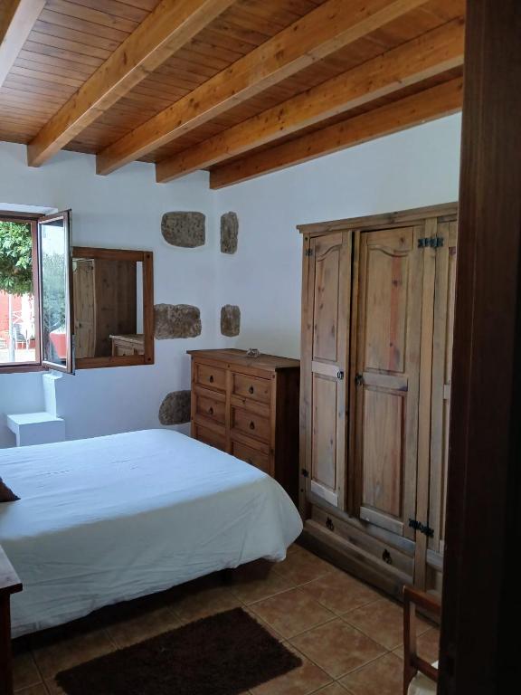a bedroom with a large bed and a wooden cabinet at Casa Rural Carmita in Vega de San Mateo