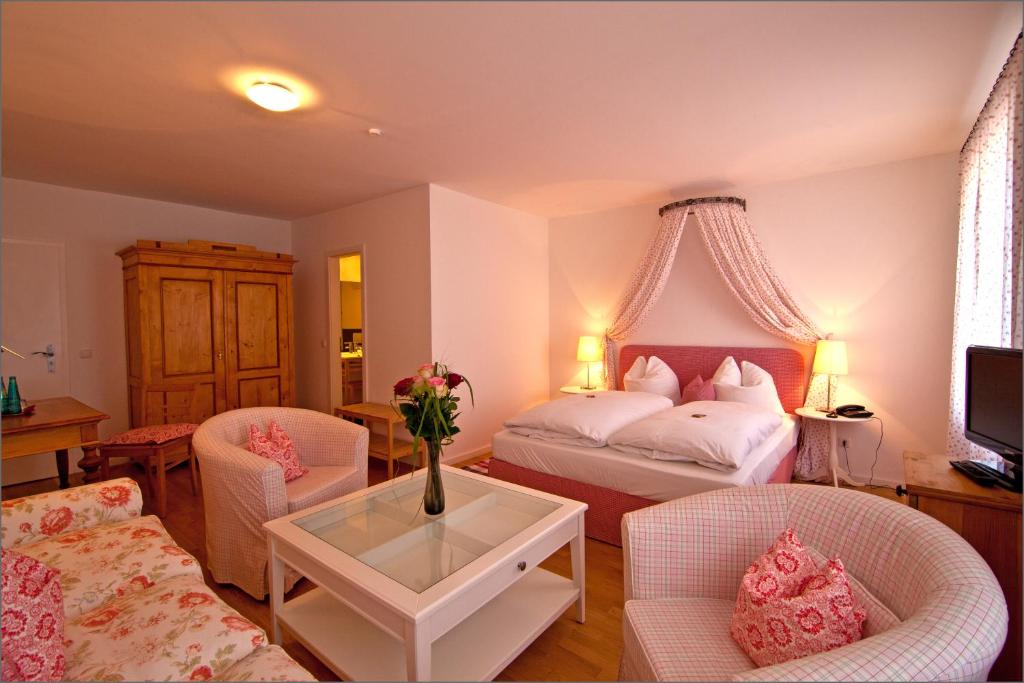 a bedroom with a bed and two chairs and a table at Altstadthotel Bauern Bräu Schrobenhausen in Schrobenhausen