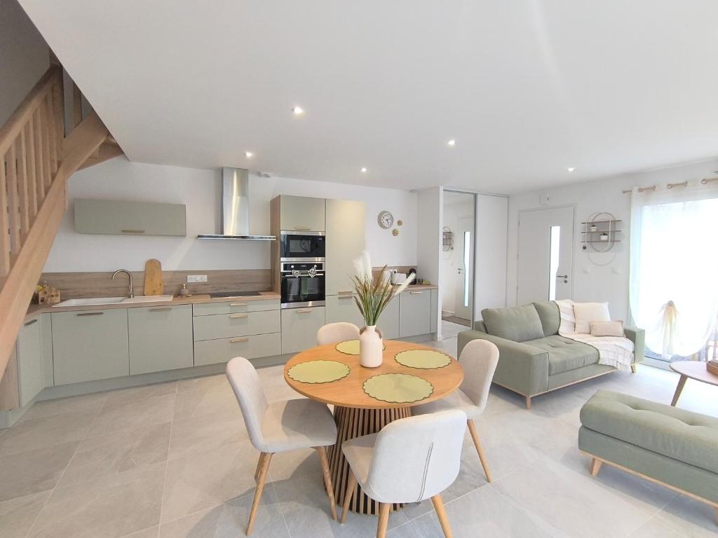 Les Dunes - Calme et Sérénité à 5 min de la Plage en voiture في Biville-sur-Mer: مطبخ وغرفة معيشة مع طاولة وكراسي