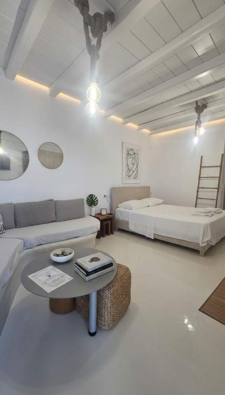 a living room with two beds and a couch and a table at Idyllic Mykonos Suite w Jacuzzi and Sea Panorama in Houlakia
