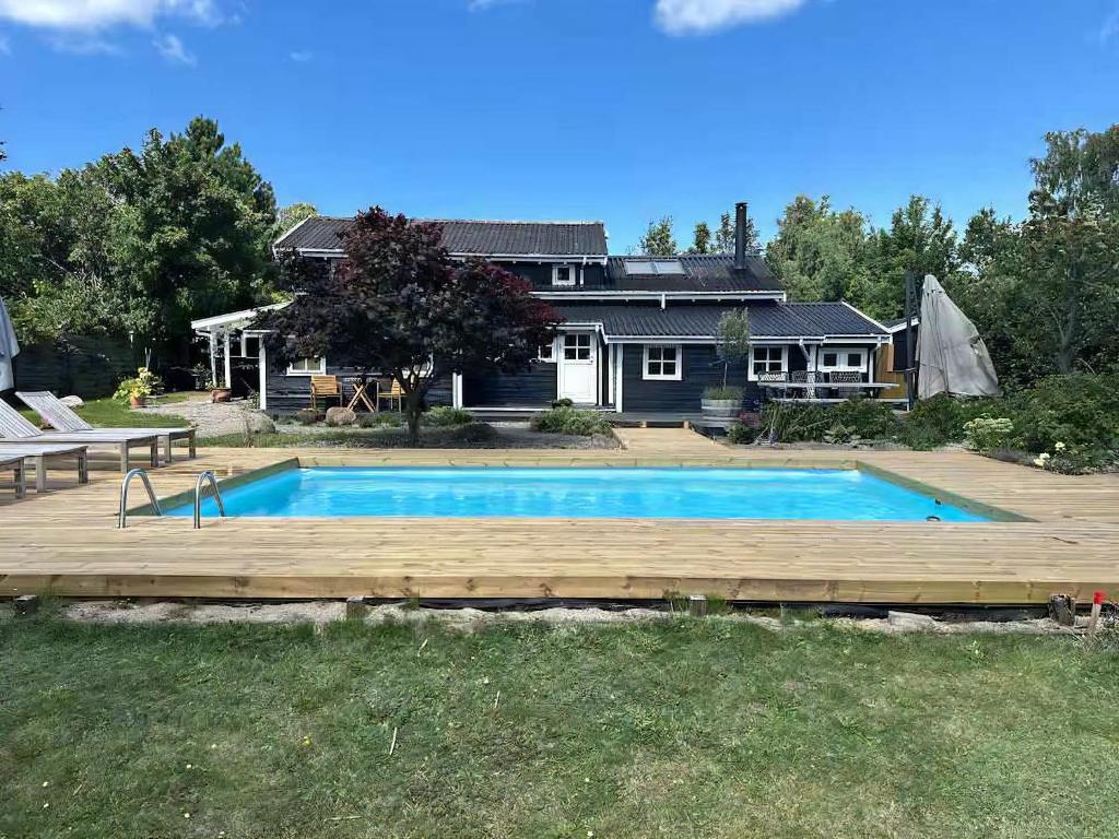 a swimming pool with a wooden deck and a house at Holiday Home With Outdoor Pool, Great Location in Hornsved