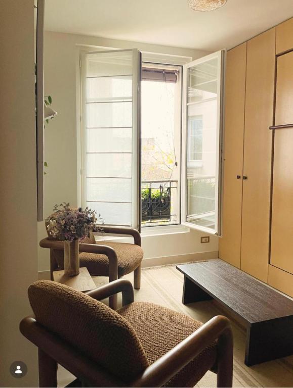 - un salon avec des chaises, une table et une fenêtre dans l'établissement Les Reliefs de Montmartre, à Paris