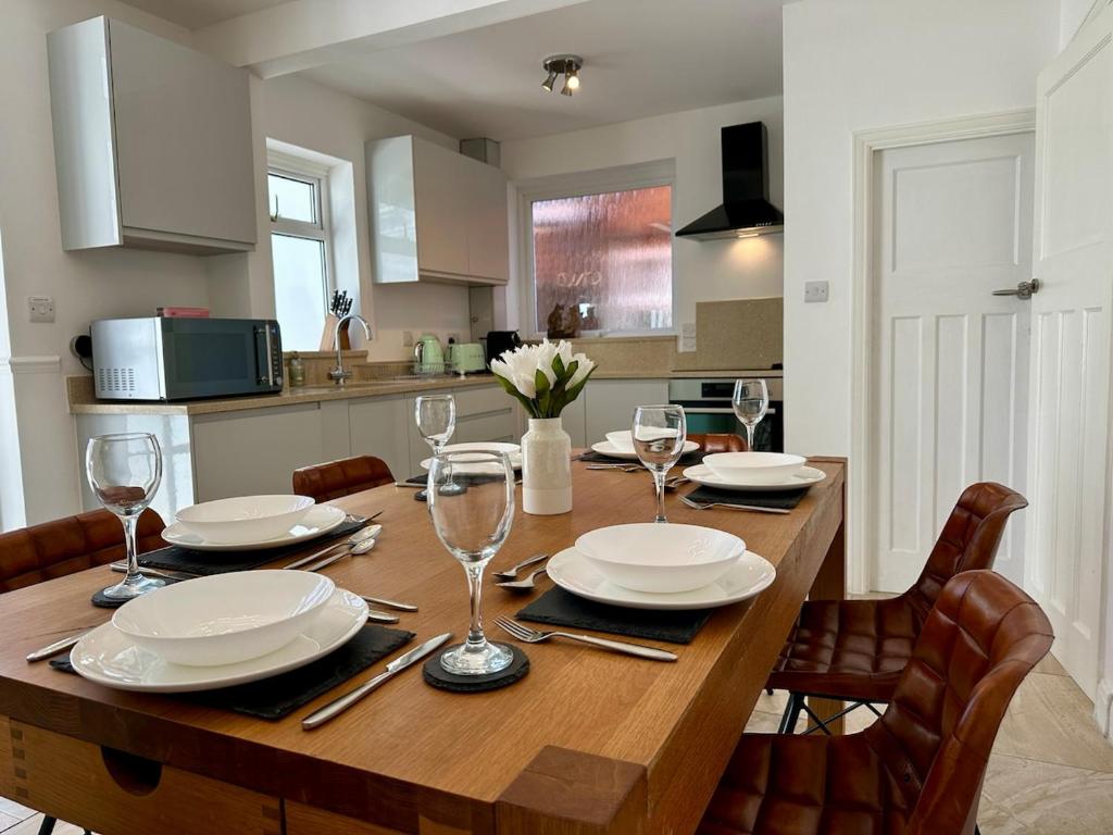 a dining room table with plates and wine glasses at 4 Bedroom House, En-Suite, 3 Doubles 1 Single, 2 Car Parking in Colchester