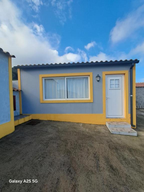 een klein blauw en geel huis met een garage bij Casa Tio Mário in Fontinhas