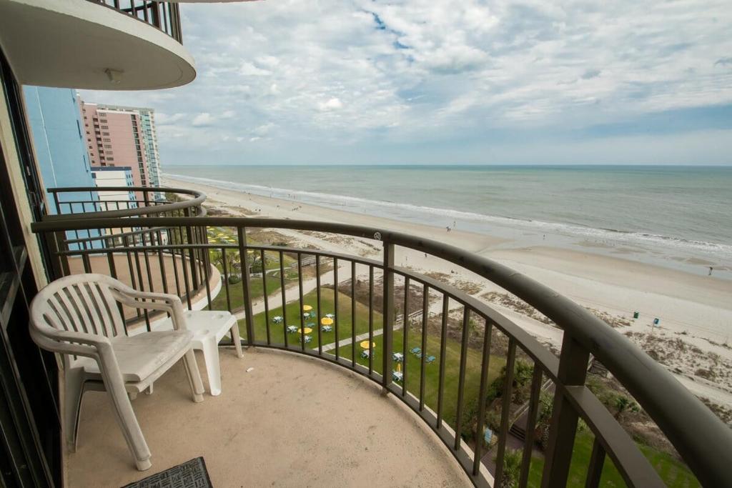 einen Balkon mit einem Stuhl und Strand in der Unterkunft Meridian Plaza 1002 in Myrtle Beach