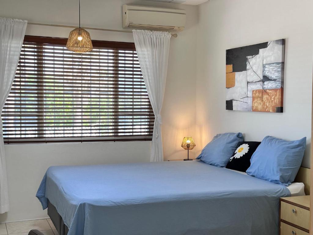 Un dormitorio con una cama con sábanas azules y una ventana. en Oasis Haven Curacao, en Willemstad
