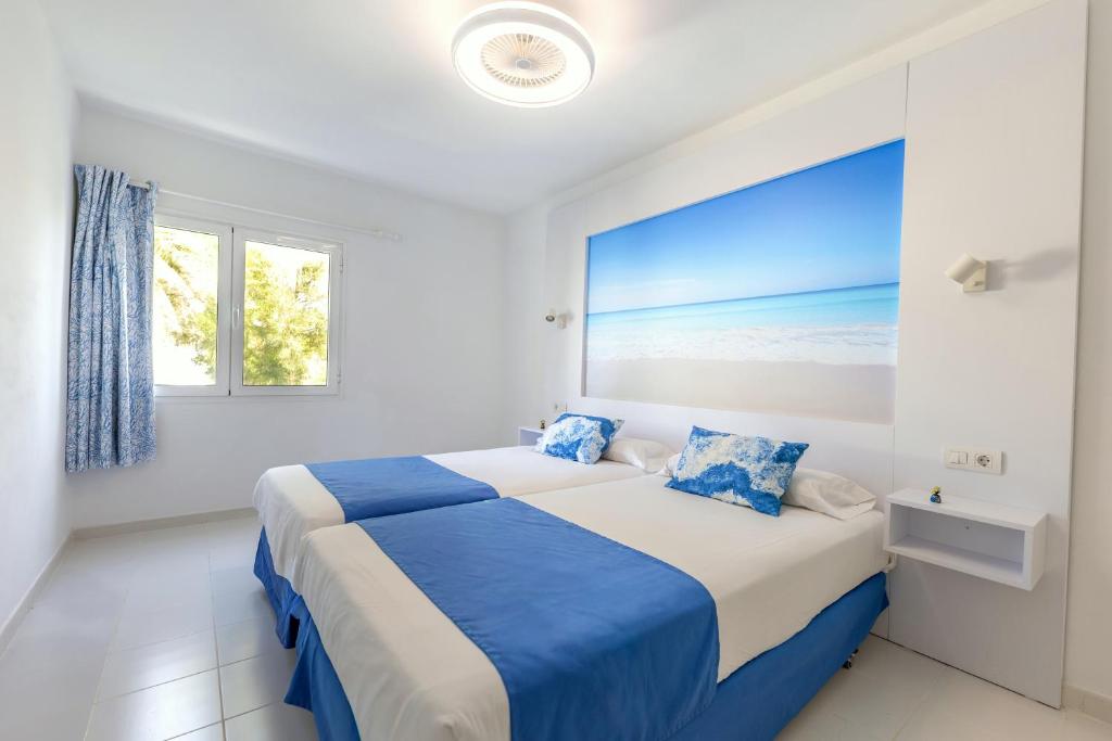 a bedroom with a bed with blue and white sheets at Apartamentos Orly Club Arena Dorada in Puerto del Carmen