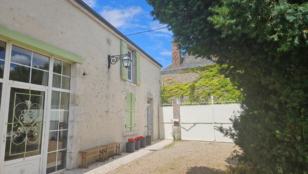 a building with a bench next to a white fence at Chambre Cheverny, Casa 103 in Messas