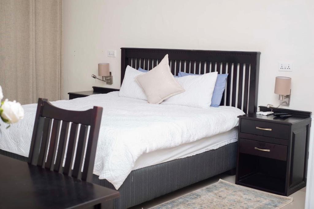 une chambre avec un grand lit avec des draps et des oreillers blancs dans l'établissement Executive comfort with premium workspace - 2334, à Kwekwe