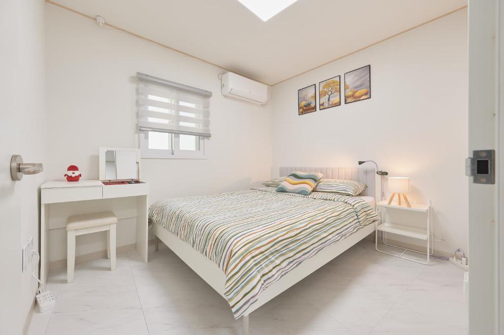 a white bedroom with a bed and a desk at Travel Home in Seoul