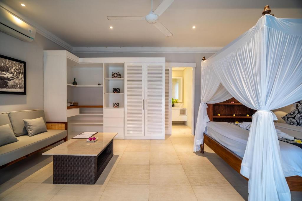 ein Schlafzimmer mit Himmelbett und Couch in der Unterkunft Raaga Samudra Villa in Padangbai