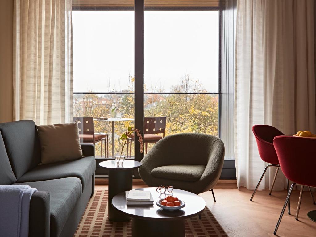 a living room with a couch and chairs and a large window at Numa Amsterdam Vondelpark in Amsterdam