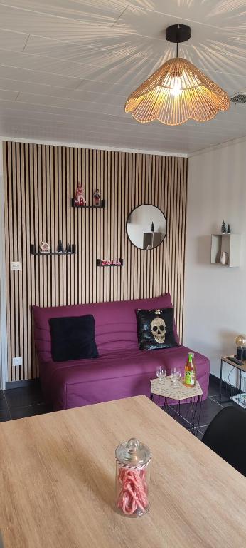 a living room with a purple couch and a table at Le Petit Clazayéen in Bressuire