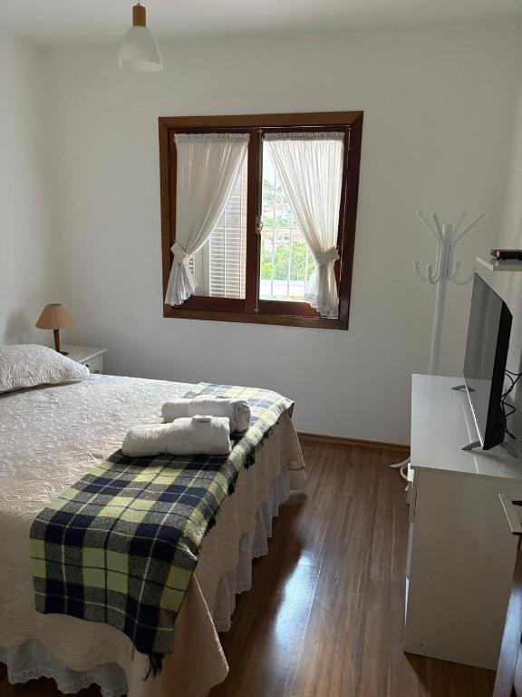 a bedroom with a bed and a window at Recanto da Vovó in Campos do Jordão