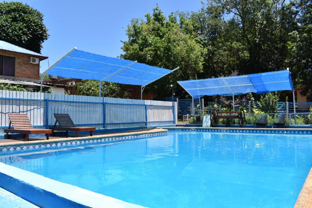 Cabañas Oberá في اوبيرا: حمام سباحة مع مظلتين زرقاوين وكرسيين