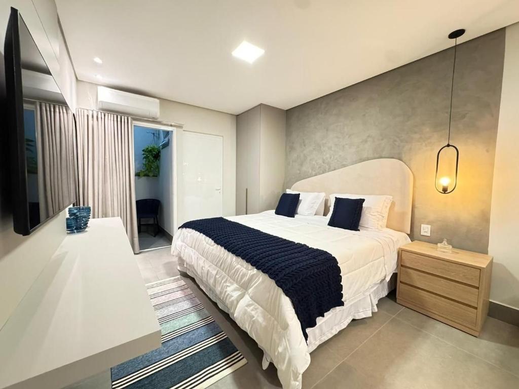 a bedroom with a large white bed with blue pillows at Tc Lofts in Uberlândia