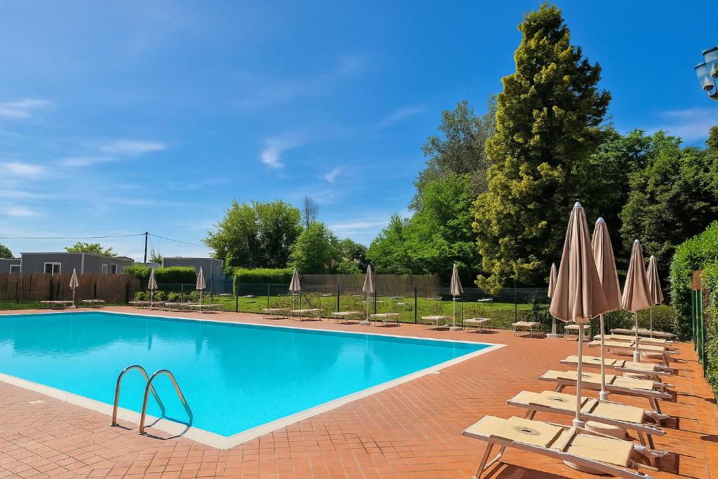 una piscina con sedie e ombrelloni di Hotiday Bologna Arena a Bologna