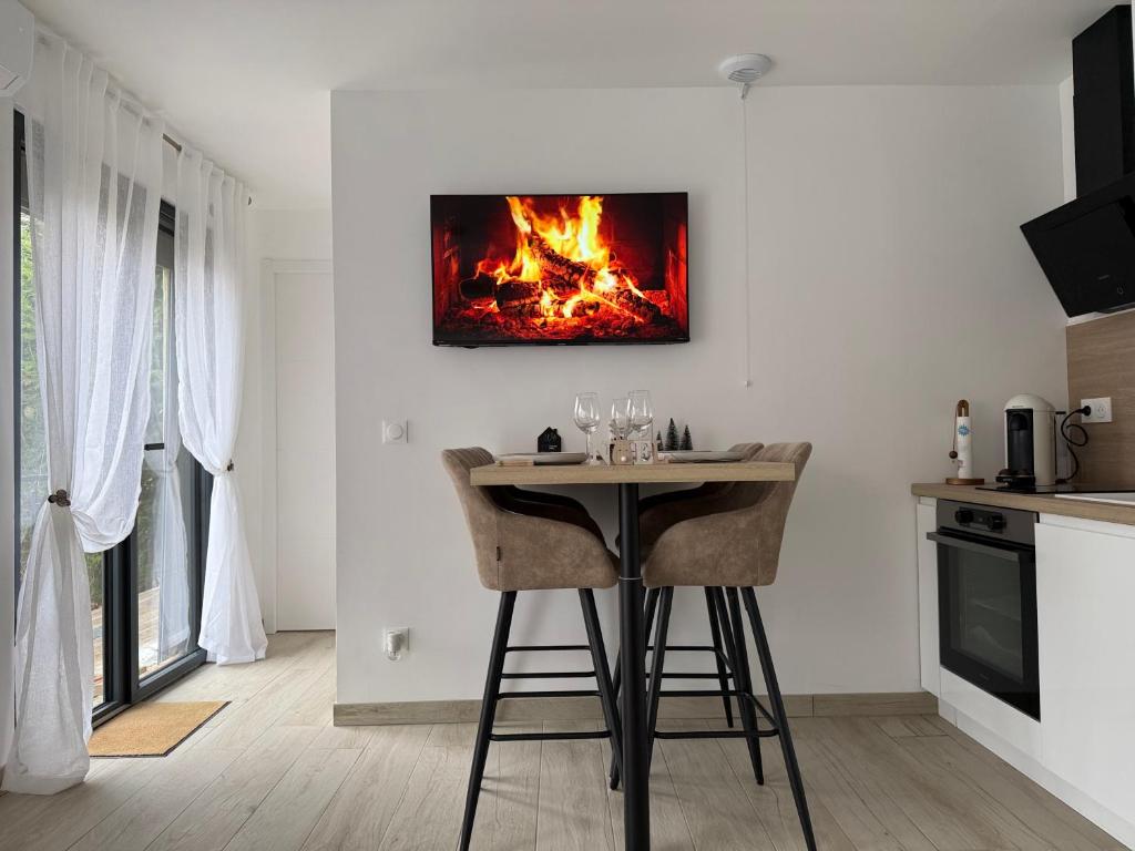 une cuisine avec une table et un feu sur le mur dans l'établissement Le Ptit Cocon Disneyland 10 min, à Coupvray